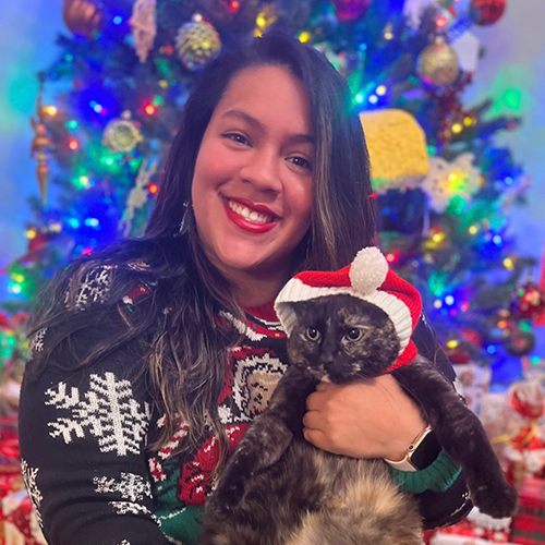 Jaritza pictured with her cat, Luna, in front of a Christmas tree.